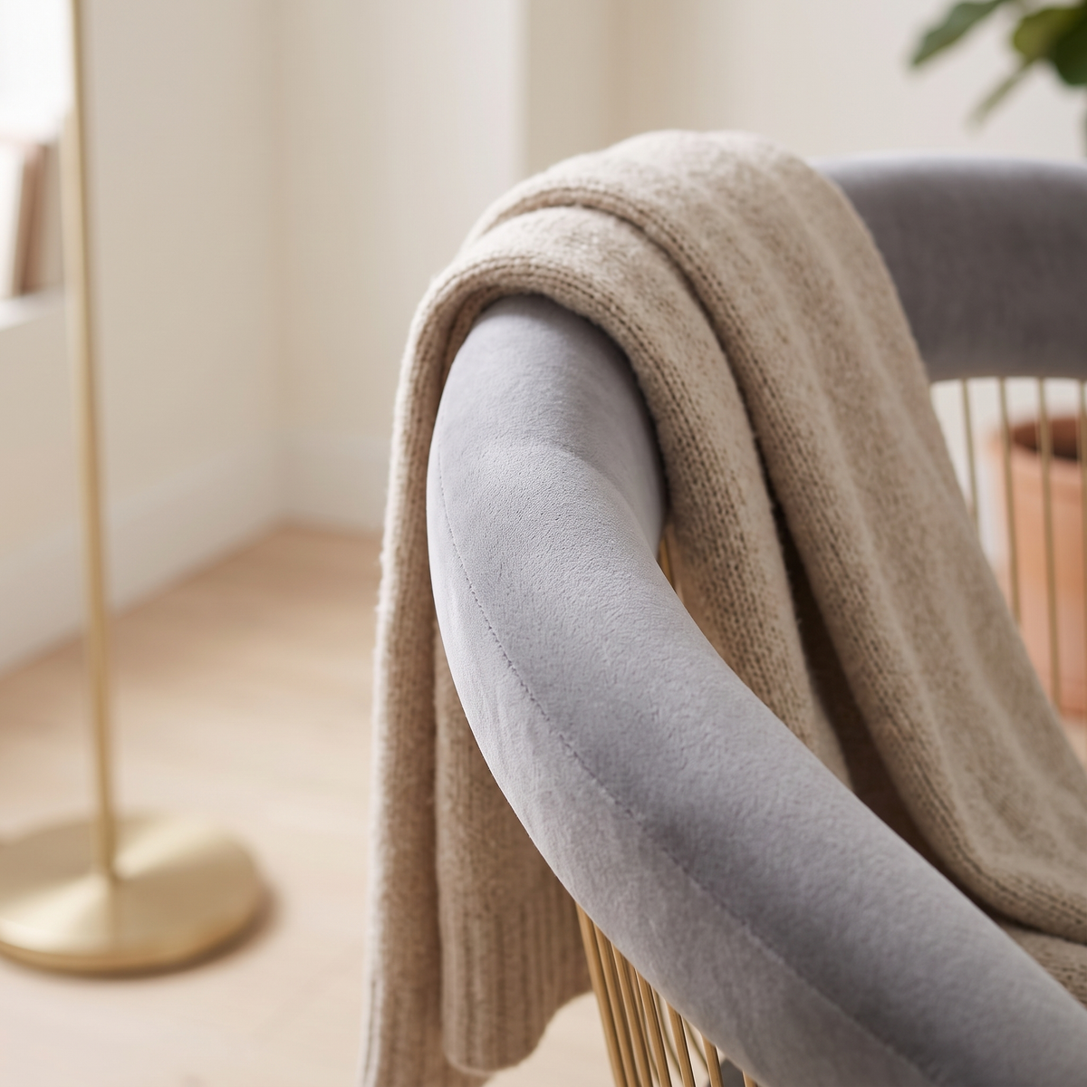 Detail of the curved grey velvet backrest with a knit throw draped over it