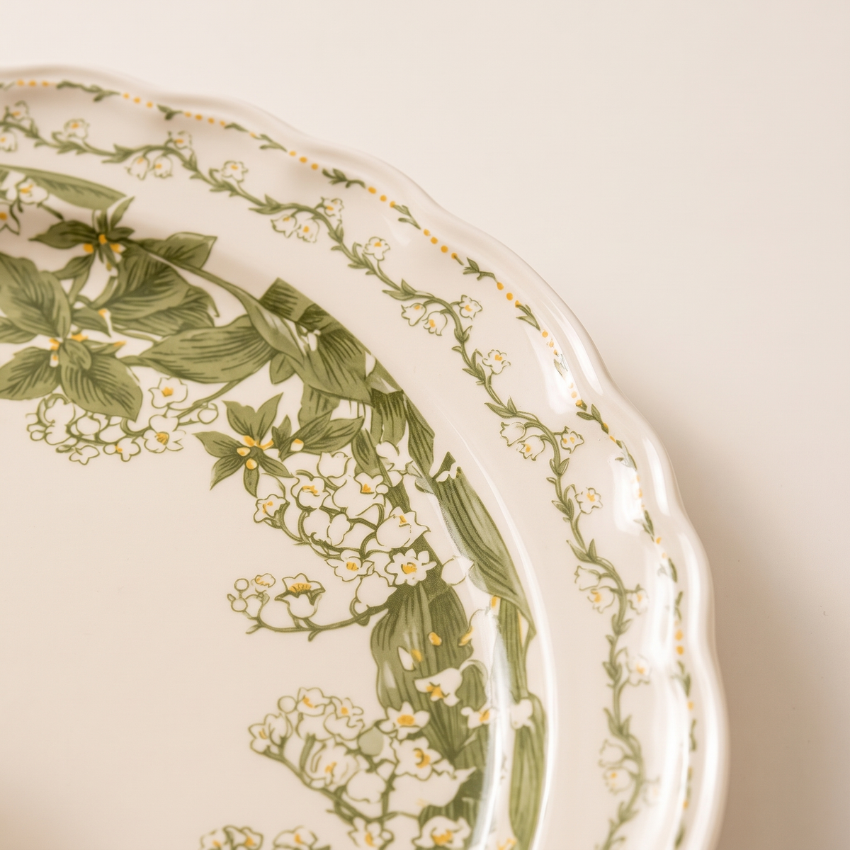 Detail of the olive-green leaf and floral pattern with scalloped border
