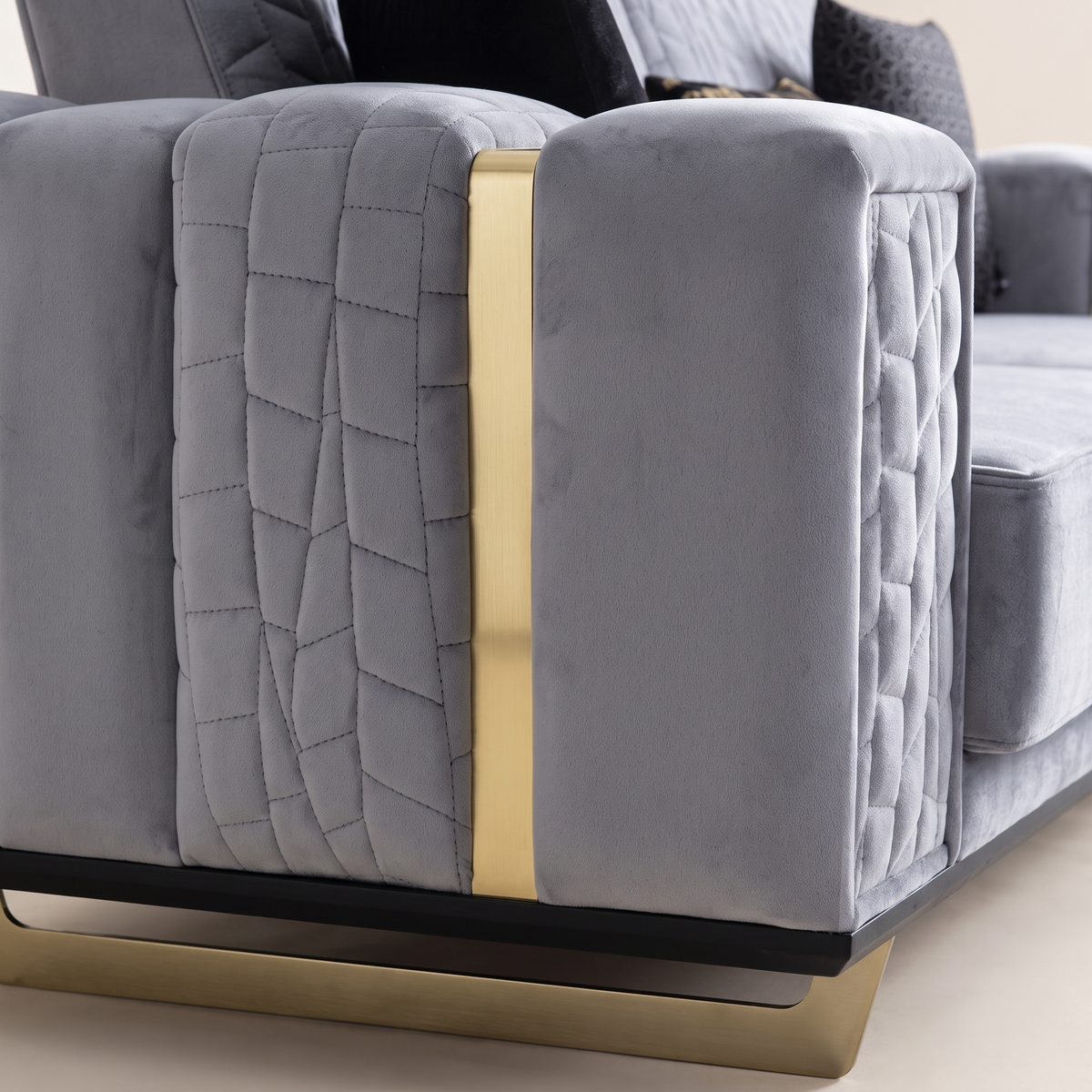 Detail of the quilted grey velvet arm and gold-finished metal strip